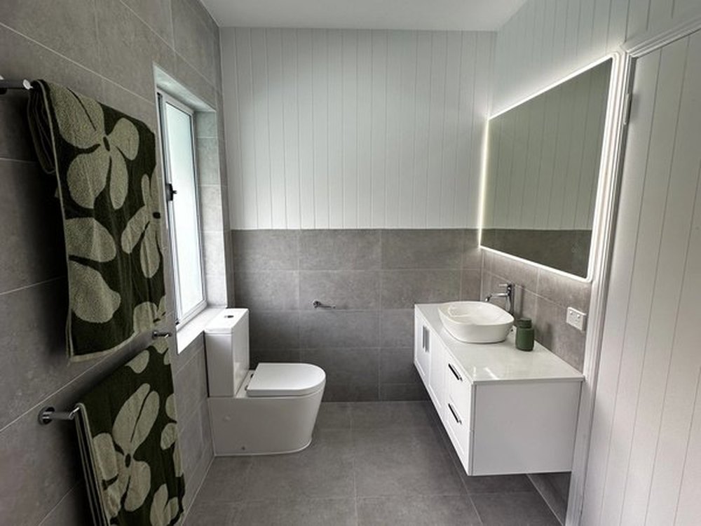 Panelled bathroom with a backlit mirror and large format floor tile