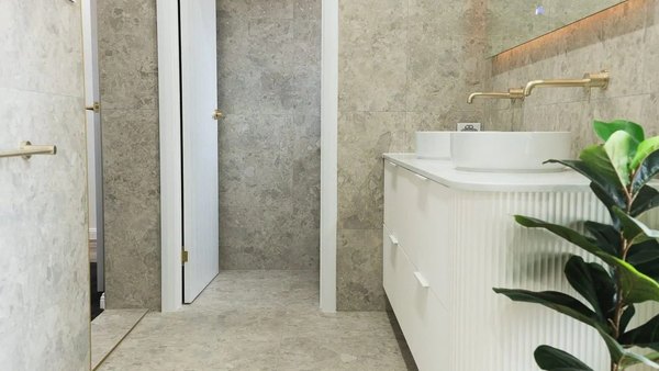 Natural travertine bathroom with a curved fluted vanity and brass fittings